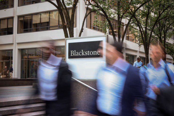 The Blackstone headquarters sign is shown outside a modern office building as several blurred people walk by.