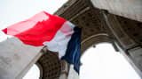 The French flag hangs above the Tomb of the Unknown Soldier at the Arc de Triomphe in Paris on May 8, 2015, during a ceremony to mark 70 years since victory over Nazi Germany during World War II. 